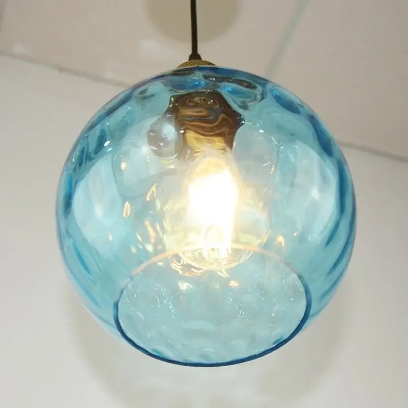 Translucent blue glass ball pendant light with textured bubble surface and brass fixture for dining room decorbites blue glass