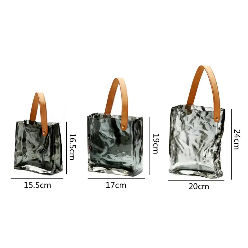 Three translucent crinkled decorbites clear glass tote bags with tan leather handles for living room decor