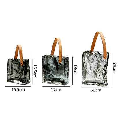 Three translucent crinkled decorbites clear glass tote bags with tan leather handles for living room decor