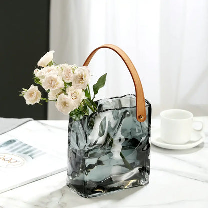 A sleek translucent gray clear glass vase with textured wave surface and tan leather handle for living room decorbites decor