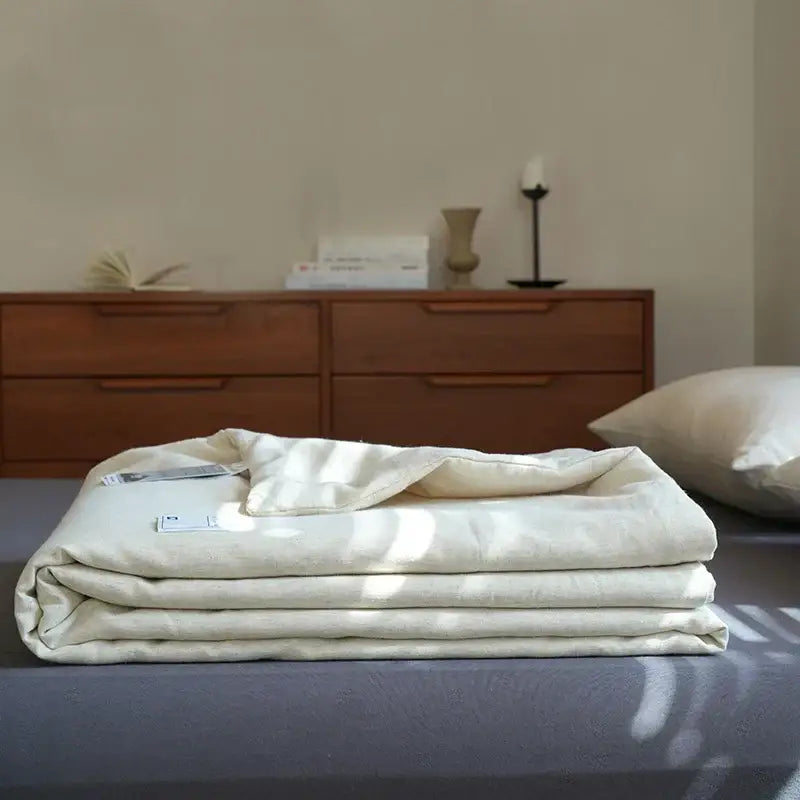 A neatly folded cream-colored linen cotton summer throw with subtle textured weave for decorbites linen cotton decor
