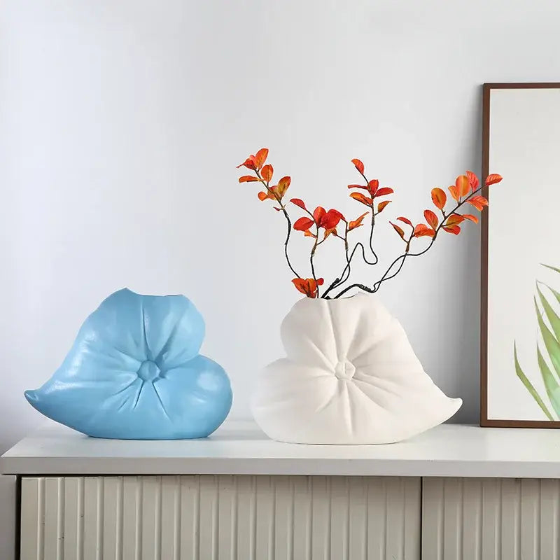 A white ceramic fluffy heart vase with a stylized lotus design holding orange and red artificial branches for decorbites fluffy heart living room decor