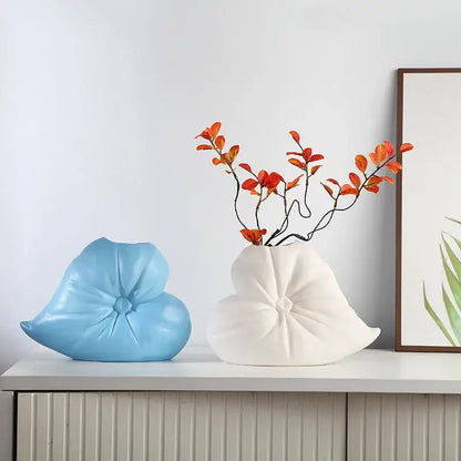 A white ceramic fluffy heart vase with a stylized lotus design holding orange and red artificial branches for decorbites fluffy heart living room decor