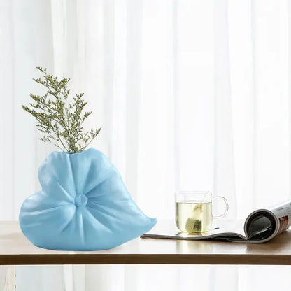 Light blue ceramic fluffy heart vase shaped like folded fabric bow holding delicate greenery for living room decorbites decor