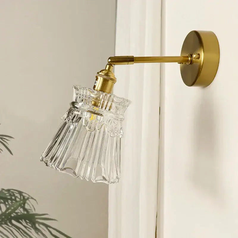 Textured glass brass mirror wall sconce featuring a clear fluted glass lampshade with a brass-finished metal arm for decorbites brass mirror