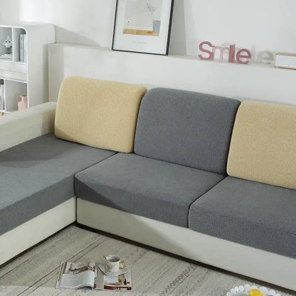 Textured green and beige fabric sofa cover with elasticized edges for living room furniture protection
