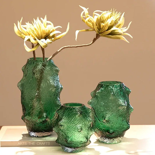 Three textured green sea cucumber glass vases with silver rims holding yellow artificial flowers for living room decor