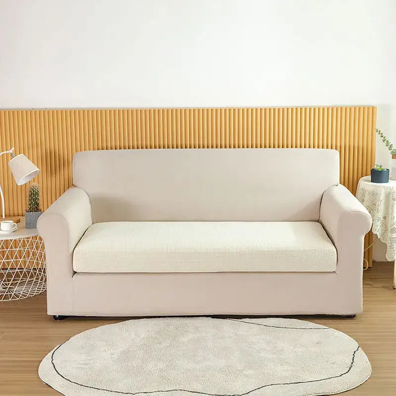 Cream-colored stretchy sofa cover with a subtle textured pattern for living room slipcover use