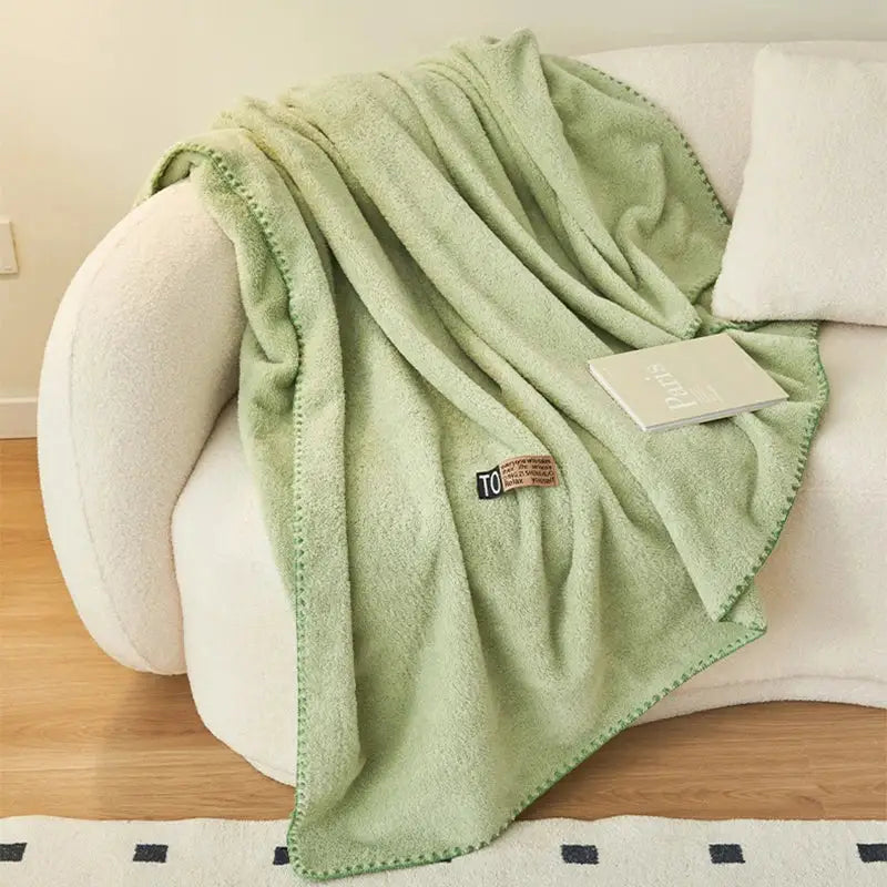A soft light green fleece decorbites cloud comforter with textured surface and neatly stitched edges for bedroom use