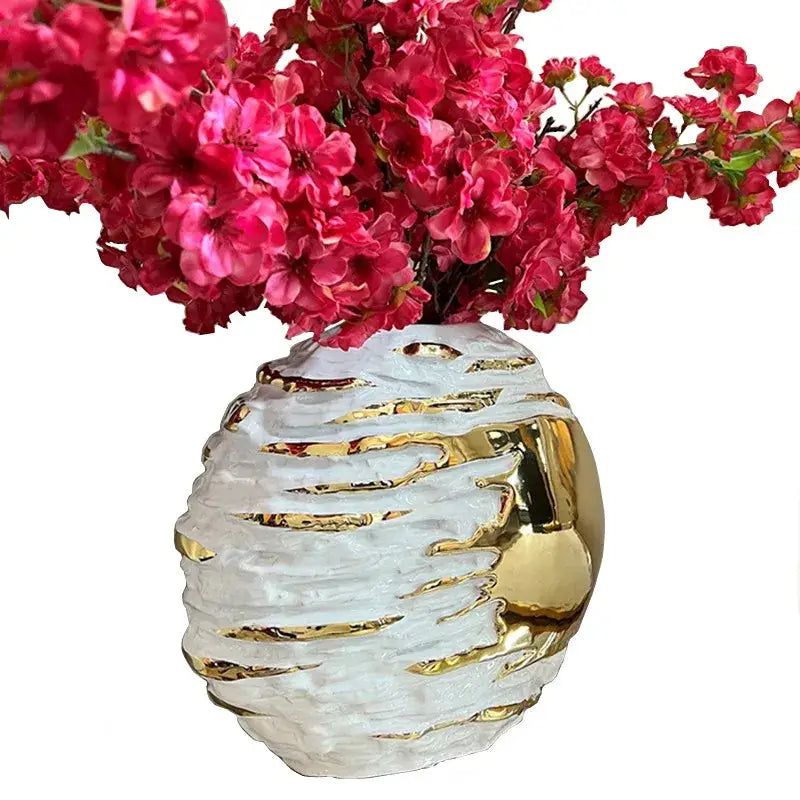 A textured white and golden ceramic vase with gold metallic accents by decorbites holds vibrant pink artificial flowers