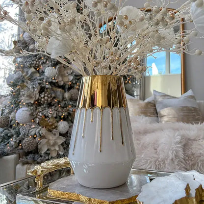 Textured white and golden ceramic vase with gold-dripped finish and fluted rim holding white pearl-decorated branches for decorbites golden ceramic decor