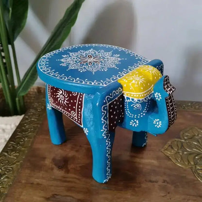 A vibrant blue decorbites handmade elephant stool with white mandala patterns and a yellow saddle for thai style ethnic decor