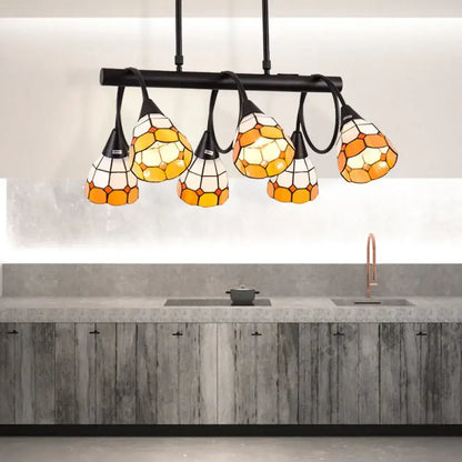 Stained glass pendant light with amber and cream hexagonal panels suspended from black metal bar for kitchen island lighting