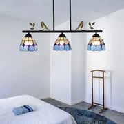 Three-light tiffany-style pendant light fixture with blue stained glass shades and a black metal curved bird shape frame