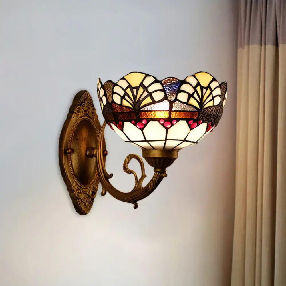 Antique brass-finished wall sconce with tiffany gold cut floral stained glass shade in cream amber and deep red hues