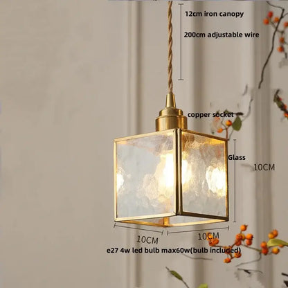 A square brass-framed pendant lamp with textured glass panels and copper socket for dining room lighting