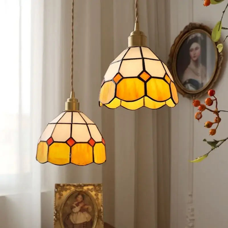 Two vintage-style tiffany green and cream stained glass led pendant lamps with brass fixtures in geometric hexagonal patterns