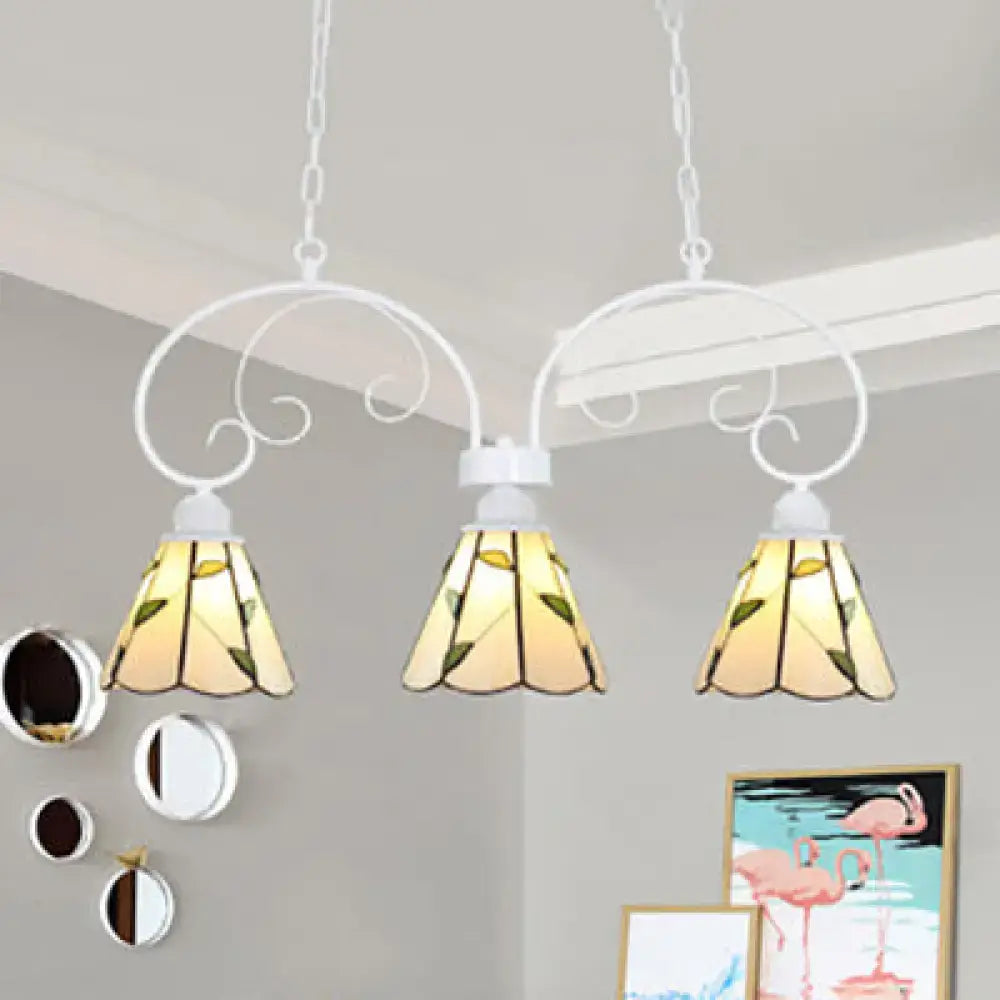 White wrought iron pendant light with three stained glass shades featuring yellow green leaf pattern and stainless glass cones