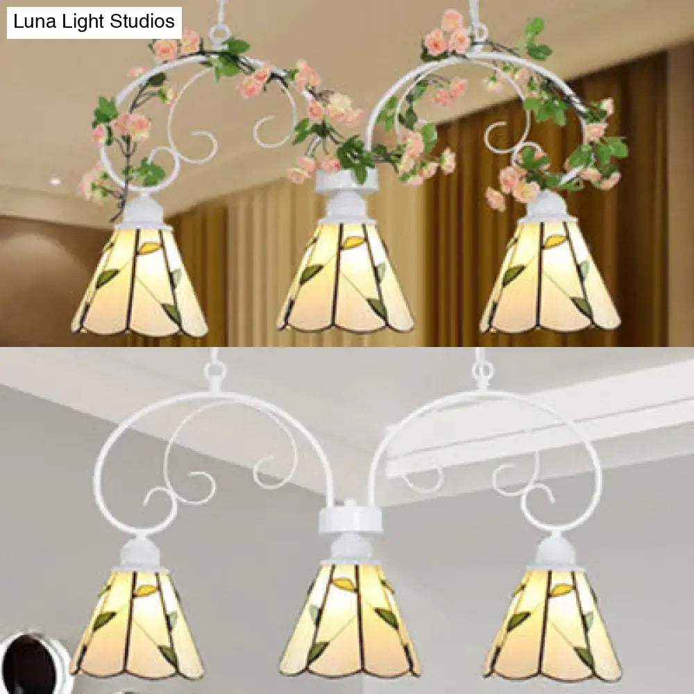 White wrought iron pendant light with three stained glass shades featuring yellow green leaf pattern and stainless glass cone