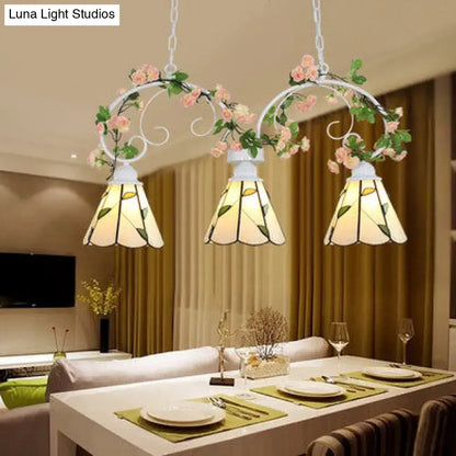 White wrought iron pendant light with leaf pattern and pink stainless glass cone shades featuring floral accents