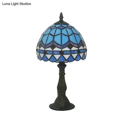 A tiffany stained glass table lamp with blue and pink dome shade and ornate dark bronze base for 110v-120v use