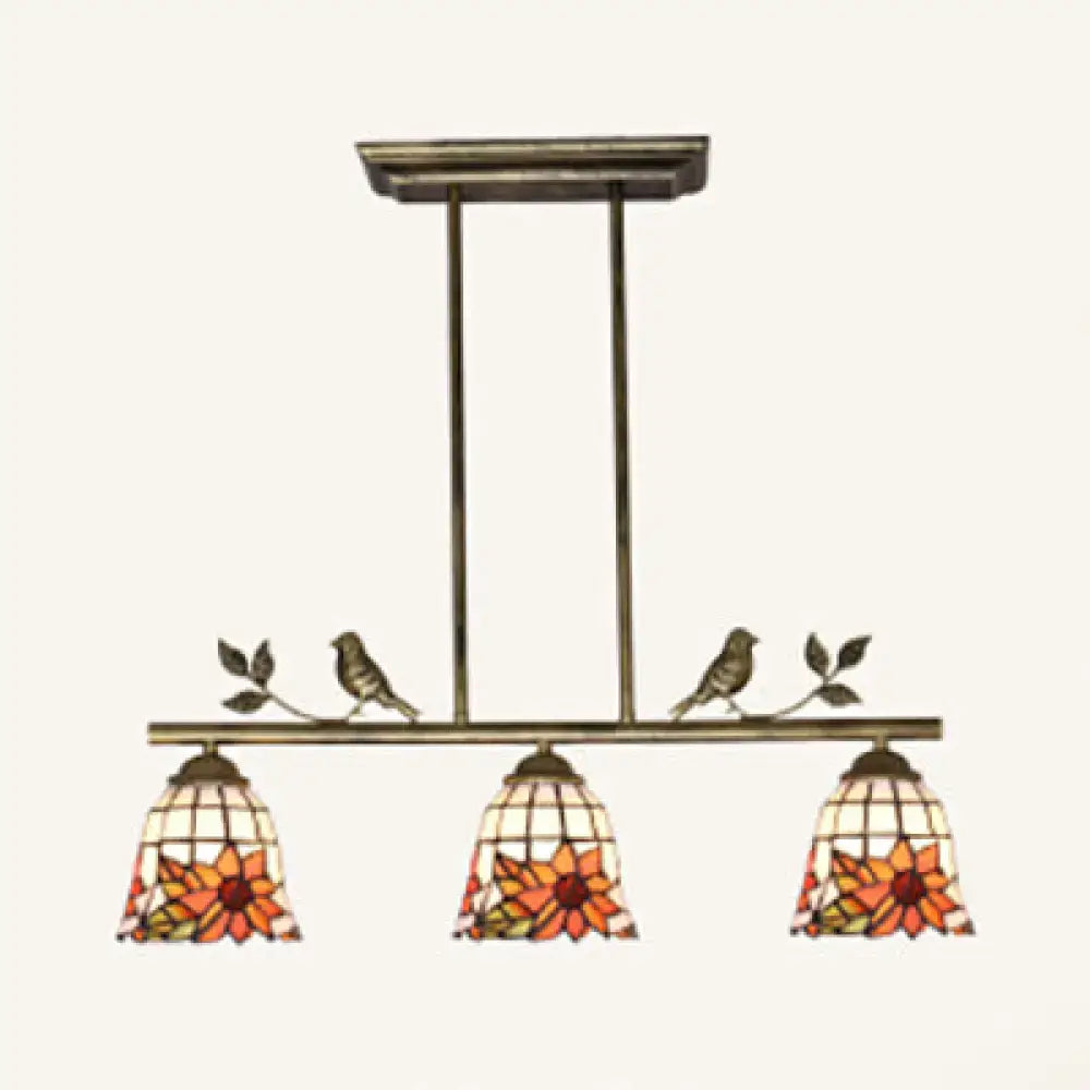 Antique brass three-light pendant fixture with stained glass sunflower shades and decorative birds by DecorBites