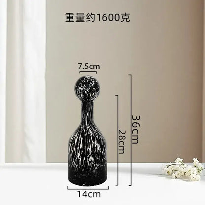 A sleek black glass decanter with a white marbled pattern and rounded stopper as decorbites leopard print decor