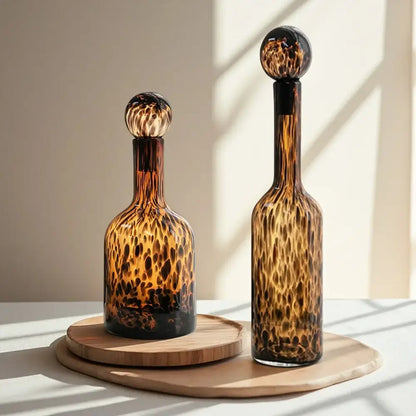 Two amber tortoiseshell glass decanters with spherical stoppers on wooden trays for decorbites leopard print decor