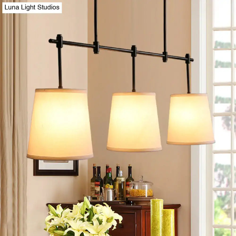 Traditional black metal pendant lighting with three cream fabric shades ideal for dining room or lights barrel island use