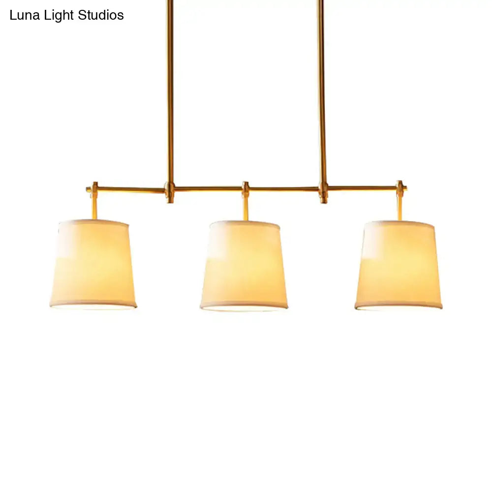 Brass-finished pendant lighting with three warm-toned fabric shades for traditional dining room or barrel island light