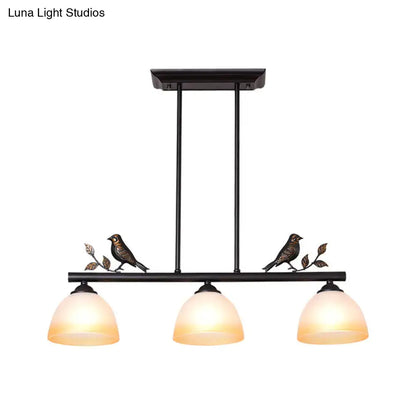 Black wrought iron ceiling light with three white glass shades and decorative bird perches for dining room island