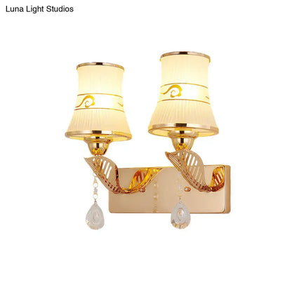 Traditional gold and cream wall sconce light with fabric shades, gold swirl patterns, and crystal teardrop pendants for dining room