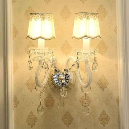 Traditional gold crystal candle wall lamp with two cream lampshades and clear crystal droplets for bedroom wall lamp