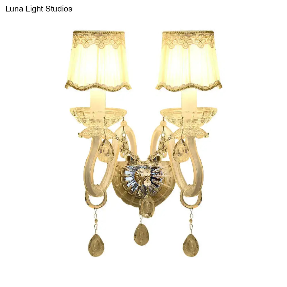 Traditional gold-toned crystal candle wall lamp with two ornate arms, lace-trimmed shades, and dangling teardrop pendants