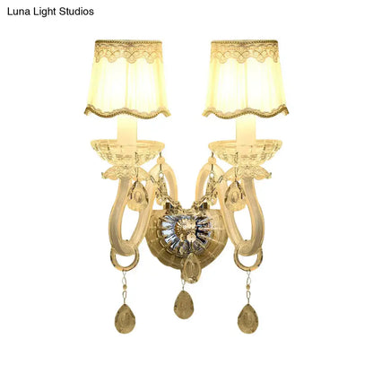 Traditional gold-toned crystal candle wall lamp with two ornate arms, lace-trimmed shades, and dangling teardrop pendants