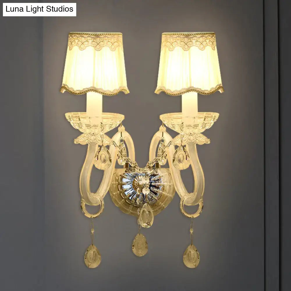 Elegant gold-tone crystal candle wall lamp with two arms, lace-trimmed cream shades, and dangling teardrop crystals