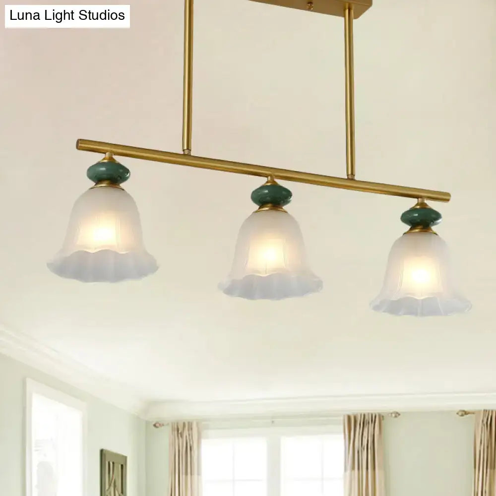 Brass finished bar pendant light with three traditional cream glass shades and teal ceramic accents for kitchen island lighting