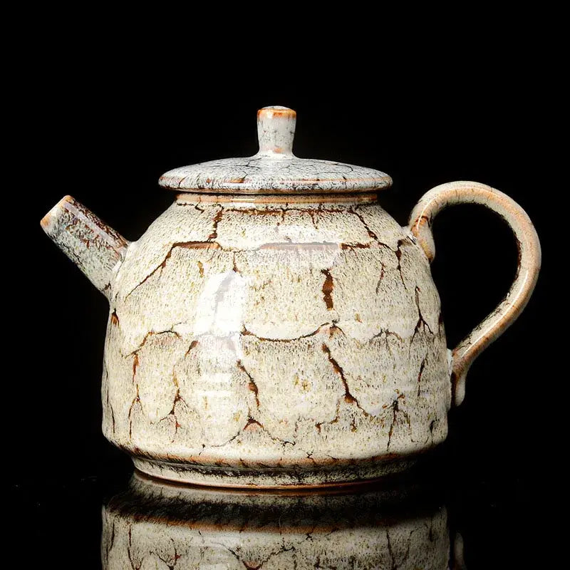 A rustic ceramic kung fu tea pot with pink and brown crackle glaze, rounded body, curved handle, and matching lid