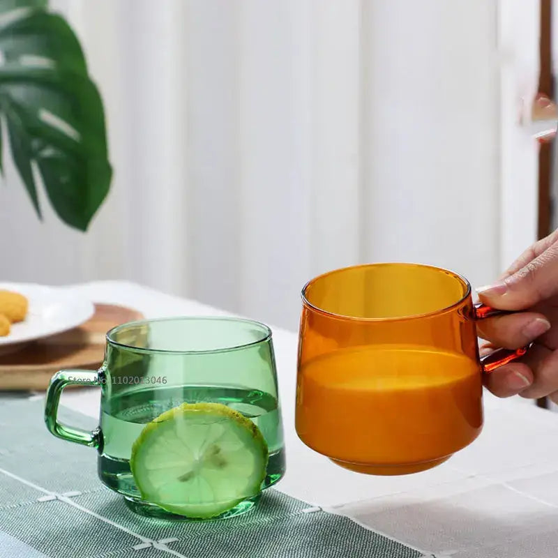 Translucent green glass coffee mug with matching handle filled with water and lemon slice heat resistant cup