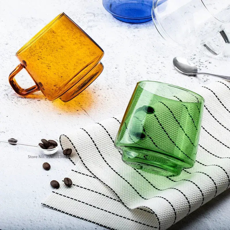 Translucent green glass coffee mug with textured surface and black accents resting on a striped cloth