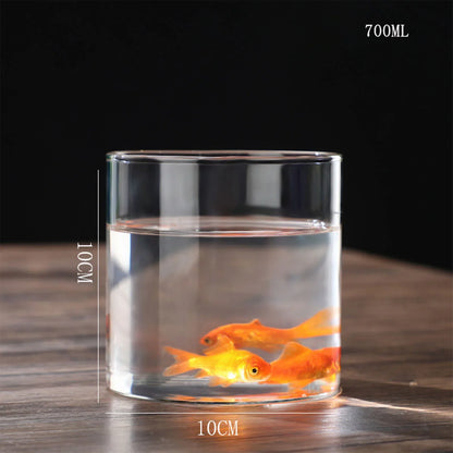 A transparent glass hydroponic vase cylinder with 10cm diameter holding water and two orange goldfish