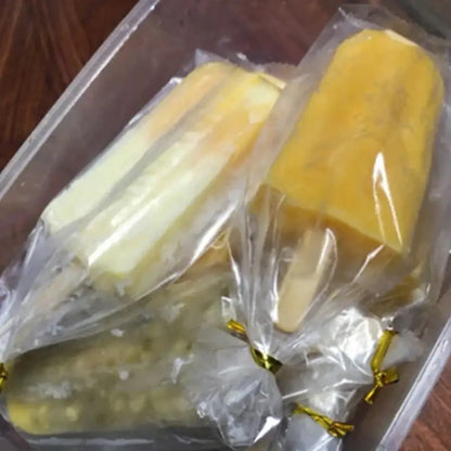Yellow and white layered ice cream in transparent pink ice cream bags tied with gold ribbons for kitchen storage