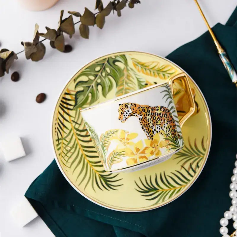 White ceramic tea cup with gold rim and leopard illustration from tropical pink and black toucan porcelain cup set