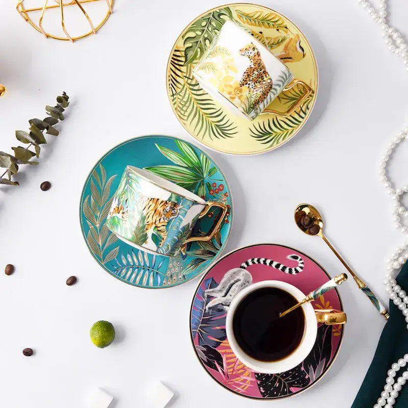 Tropical pink and black toucan porcelain tea cup set with gold-trimmed handles and jungle animal designs on glossy cups