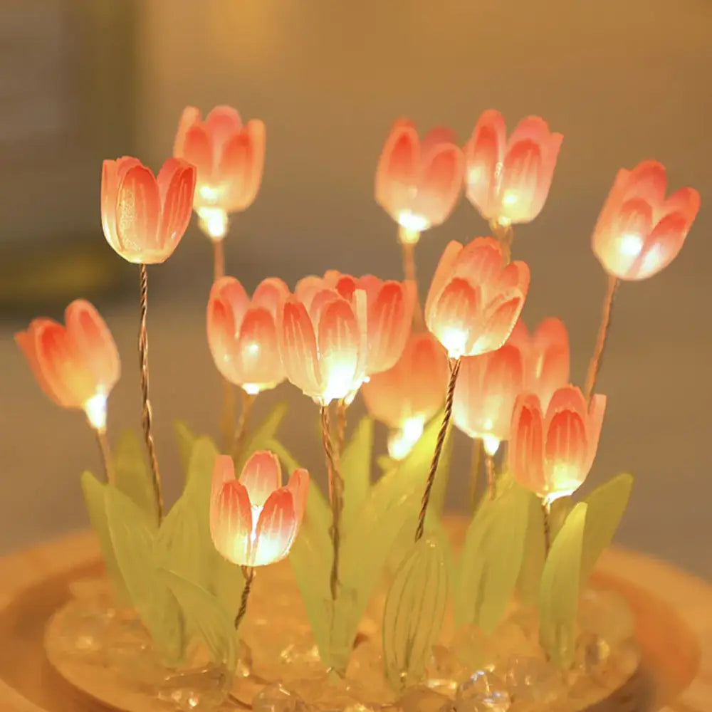 A cluster of glowing pink tulip night light led lamps with green leaves on a decorative base for bedside use