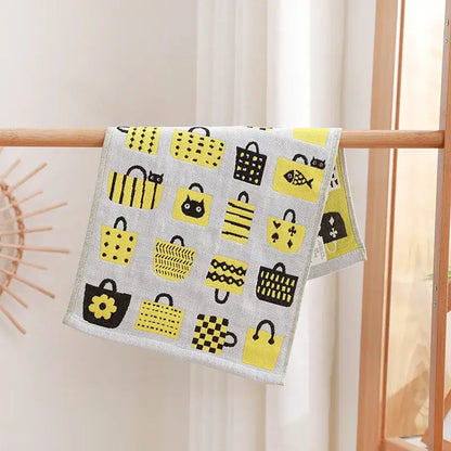 A gray decorbites cotton gauze face towel with yellow and black shopping bags and playful cat and flower patterns