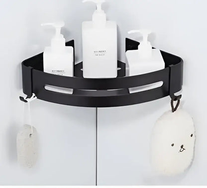 Two tier black aluminum corner shelf bathroom caddy holding three white pump bottles and hanging plush soap dish