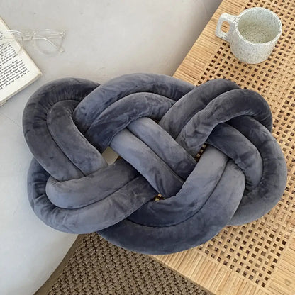 A dark gray velvet knot throw pillow with a soft textured surface for living room decorative use