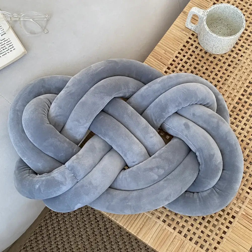 A light blue velvet knot throw pillow with a soft textured surface and interwoven loops for living room decor