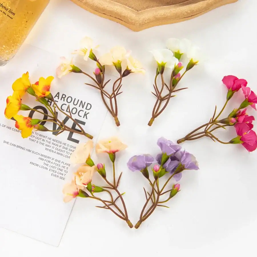A collection of decorbites artificial flowers featuring vibrant yellow pink white and purple cherry blossom sprigs with slender brown stems